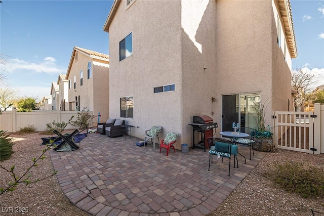 back of property with a gate, a patio area, fence, and stucco siding