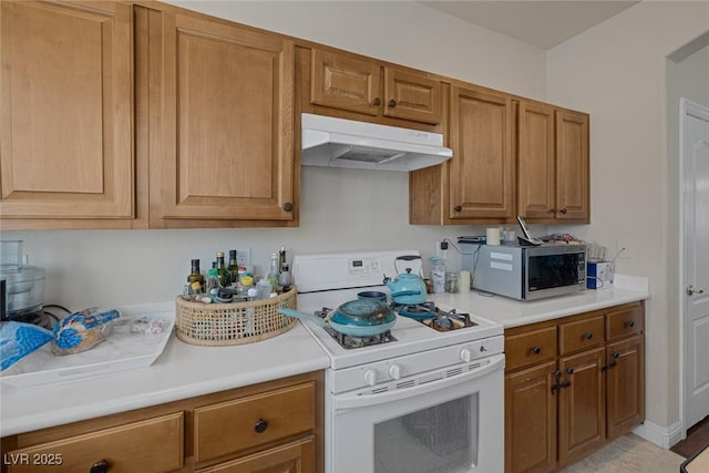 kitchen with under cabinet range hood, stainless steel microwave, light countertops, and gas range gas stove