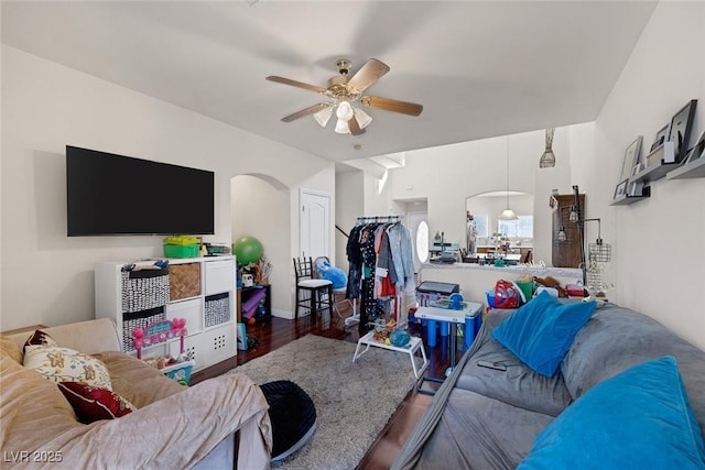 living area featuring arched walkways, wood finished floors, and a ceiling fan