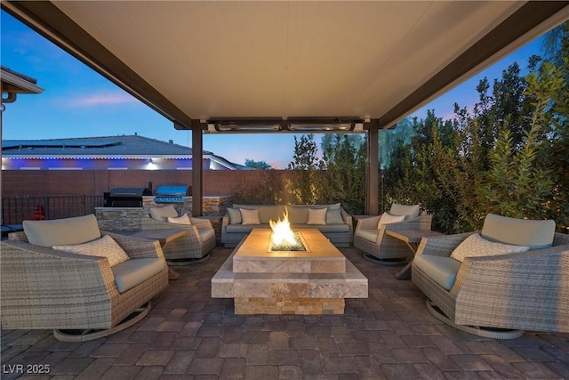 view of patio with an outdoor kitchen, a grill, an outdoor living space with a fire pit, and fence