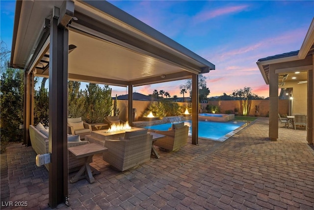 pool at dusk with a patio, a fire pit, and a pool with connected hot tub