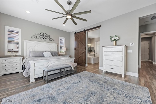 bedroom featuring a barn door, baseboards, and wood finished floors