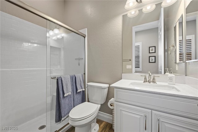 bathroom featuring vanity, a shower stall, toilet, and wood finished floors