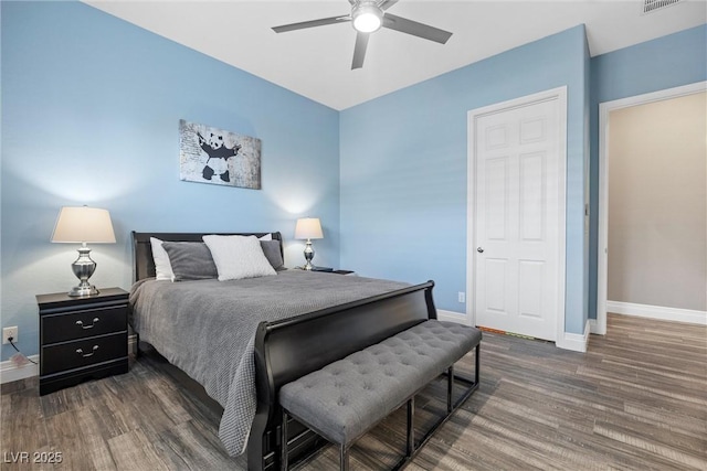 bedroom featuring a ceiling fan, visible vents, wood finished floors, and baseboards