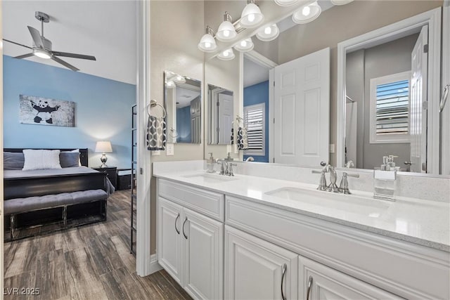 full bath featuring ceiling fan, double vanity, wood finished floors, and a sink