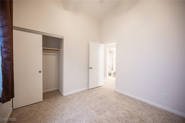 unfurnished bedroom with a closet, baseboards, carpet, and high vaulted ceiling