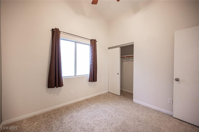 unfurnished bedroom with ceiling fan, baseboards, carpet, vaulted ceiling, and a closet