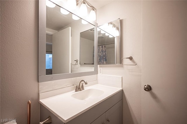 bathroom featuring tasteful backsplash, vanity, and a textured wall