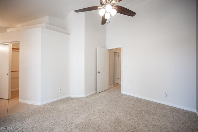 unfurnished room with baseboards, light carpet, a high ceiling, and ceiling fan