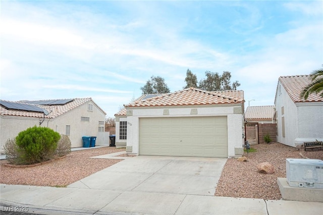 mediterranean / spanish home with stucco siding, concrete driveway, a garage, a tile roof, and roof mounted solar panels