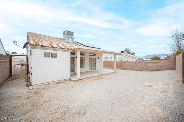 back of house with stucco siding, a tile roof, central AC, a fenced backyard, and a patio area