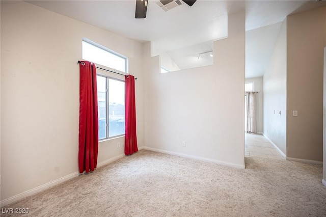 carpeted spare room with visible vents, track lighting, baseboards, ceiling fan, and vaulted ceiling