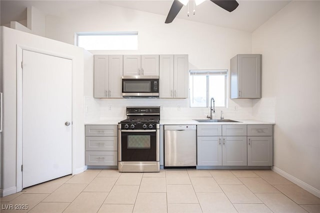 kitchen with decorative backsplash, gray cabinetry, stainless steel appliances, and a sink