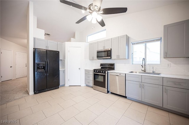 kitchen with vaulted ceiling, gray cabinets, appliances with stainless steel finishes, and a sink