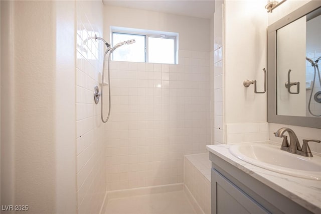 full bath featuring tiled shower and vanity