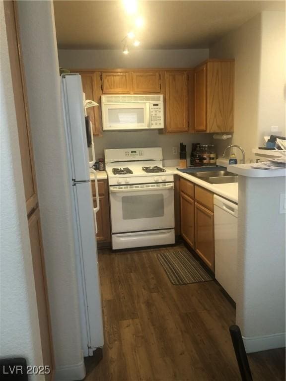 kitchen featuring a sink, white appliances, dark wood-type flooring, and light countertops