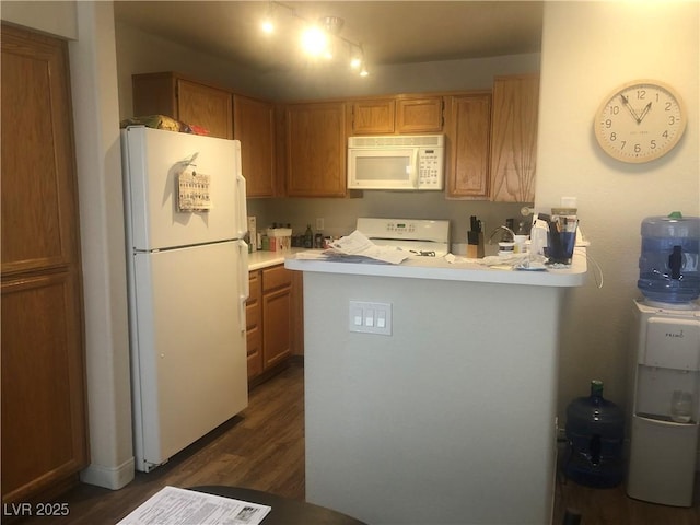 kitchen with dark wood-type flooring, white appliances, a peninsula, brown cabinetry, and light countertops