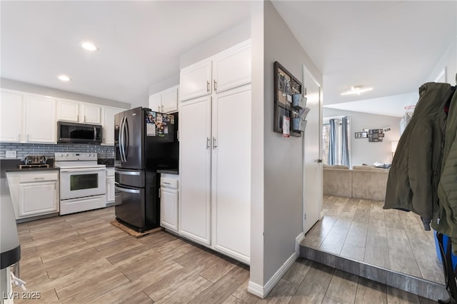 kitchen with electric range, light wood-style flooring, freestanding refrigerator, white cabinetry, and stainless steel microwave