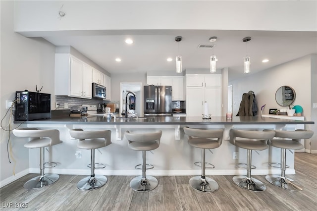 kitchen featuring dark countertops, visible vents, tasteful backsplash, appliances with stainless steel finishes, and a peninsula