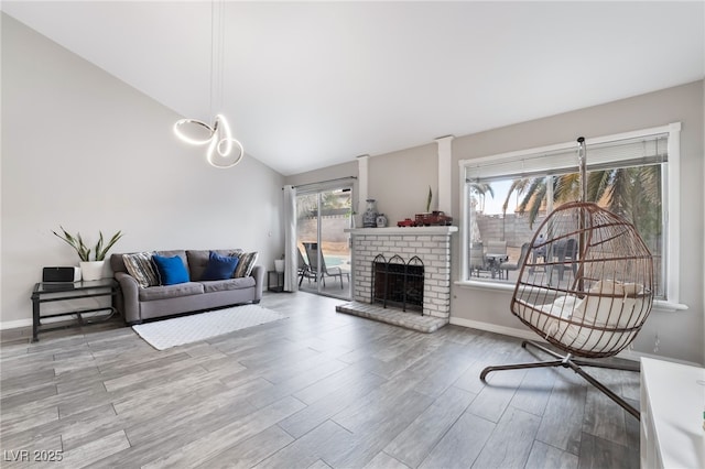 living area featuring baseboards, lofted ceiling, wood finished floors, and a fireplace