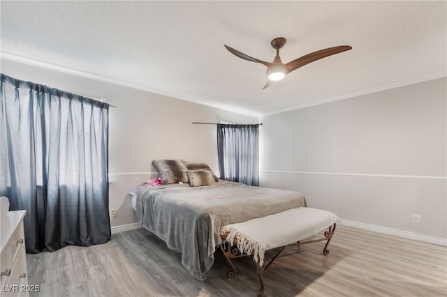 bedroom featuring light wood-style flooring, crown molding, and baseboards