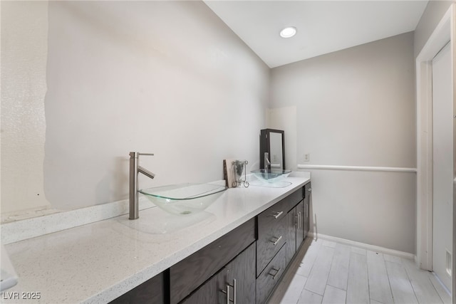 bathroom featuring double vanity, wood finished floors, baseboards, and a sink