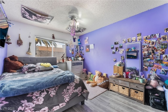 bedroom with a ceiling fan, wood finished floors, and a textured ceiling