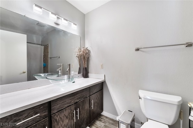 bathroom featuring toilet, curtained shower, wood finished floors, baseboards, and vanity