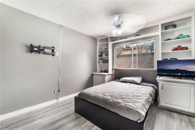 bedroom with light wood-type flooring, baseboards, and a textured ceiling