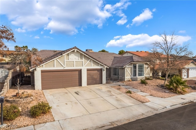 tudor house with a tile roof, concrete driveway, an attached garage, and fence