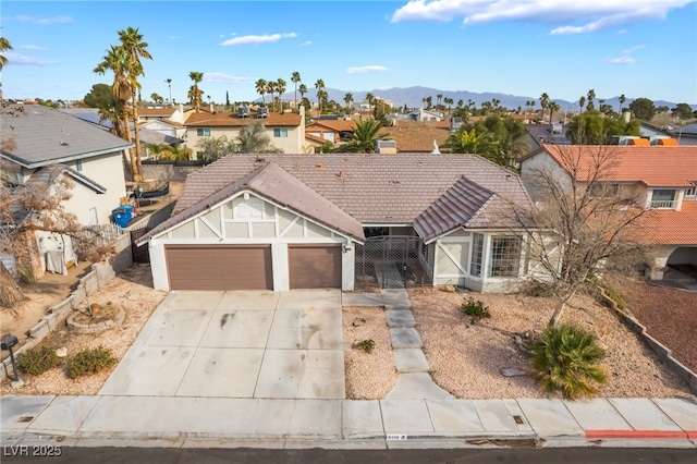 view of front facade featuring an attached garage, fence, a residential view, driveway, and a mountain view