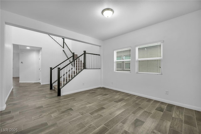 empty room featuring stairway, wood finished floors, and baseboards