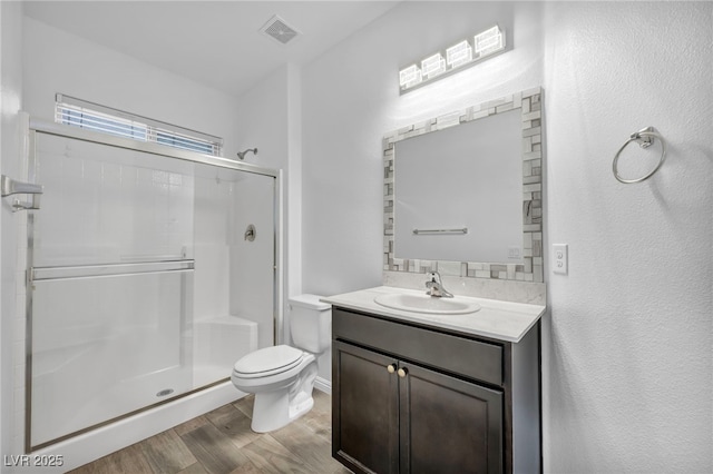 full bathroom featuring visible vents, toilet, a stall shower, wood finished floors, and vanity