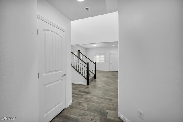 corridor featuring baseboards, wood finished floors, and stairs