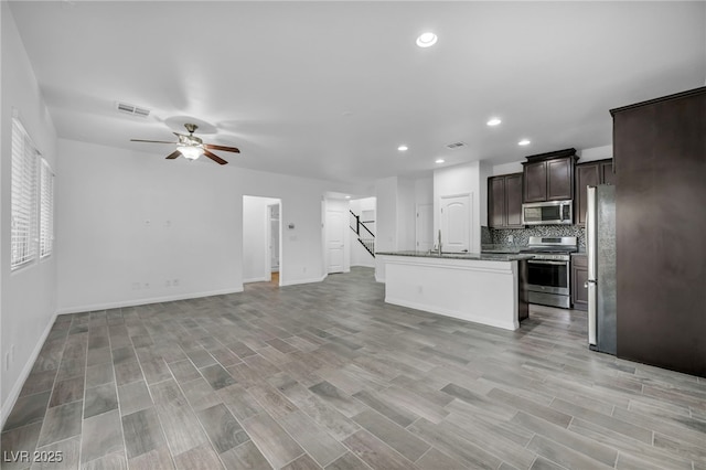 kitchen with visible vents, a ceiling fan, open floor plan, stainless steel appliances, and dark brown cabinets