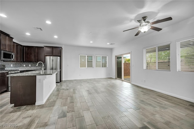 kitchen with visible vents, open floor plan, stainless steel appliances, decorative backsplash, and ceiling fan