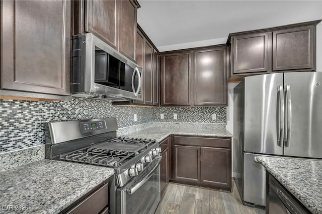 kitchen with dark brown cabinets, decorative backsplash, and appliances with stainless steel finishes