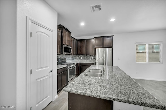 kitchen featuring visible vents, backsplash, dark brown cabinetry, stainless steel appliances, and a sink