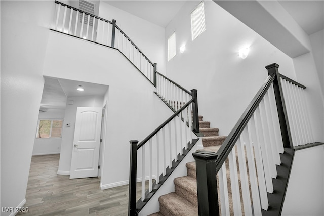 stairs featuring baseboards, a high ceiling, and wood finished floors