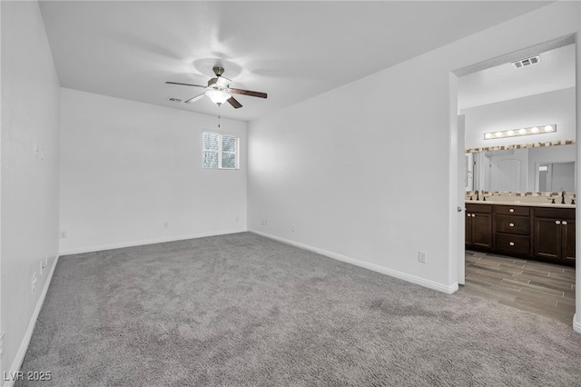 unfurnished bedroom with baseboards, light colored carpet, visible vents, and a sink