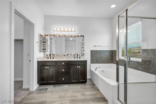 full bath featuring a bath, a shower stall, double vanity, and a sink