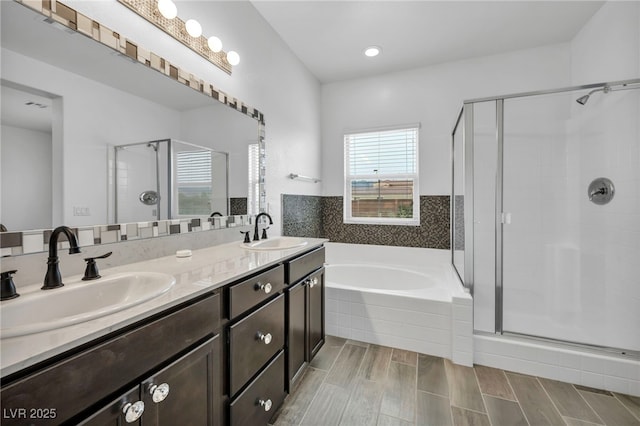 bathroom featuring a stall shower, a garden tub, and a sink