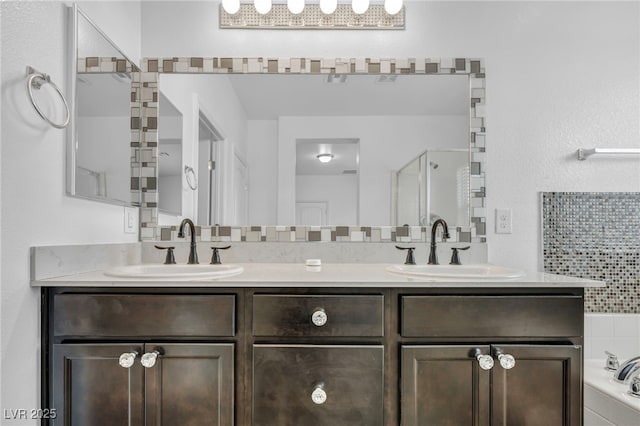 bathroom with double vanity, a shower with door, a garden tub, and a sink