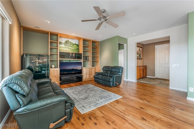 living room featuring ceiling fan, baseboards, and wood finished floors