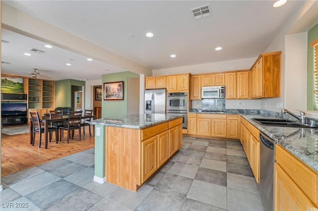 kitchen with a sink, visible vents, stone counters, and appliances with stainless steel finishes