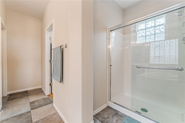 bathroom featuring a shower stall and baseboards