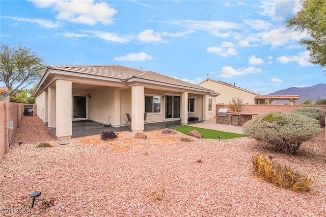 back of house featuring stucco siding, an outdoor kitchen, a fenced backyard, and a patio area