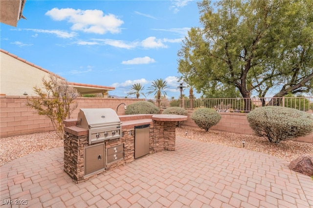 view of patio with area for grilling, exterior kitchen, and a fenced backyard