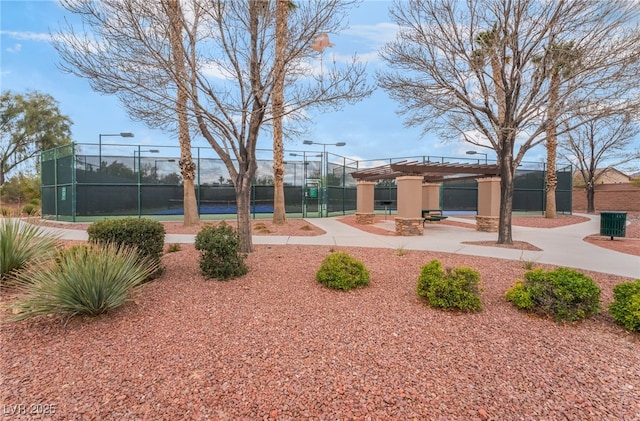 view of home's community with a tennis court, a pergola, and fence