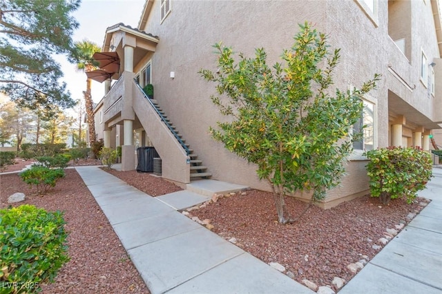 view of home's exterior with stairway and stucco siding